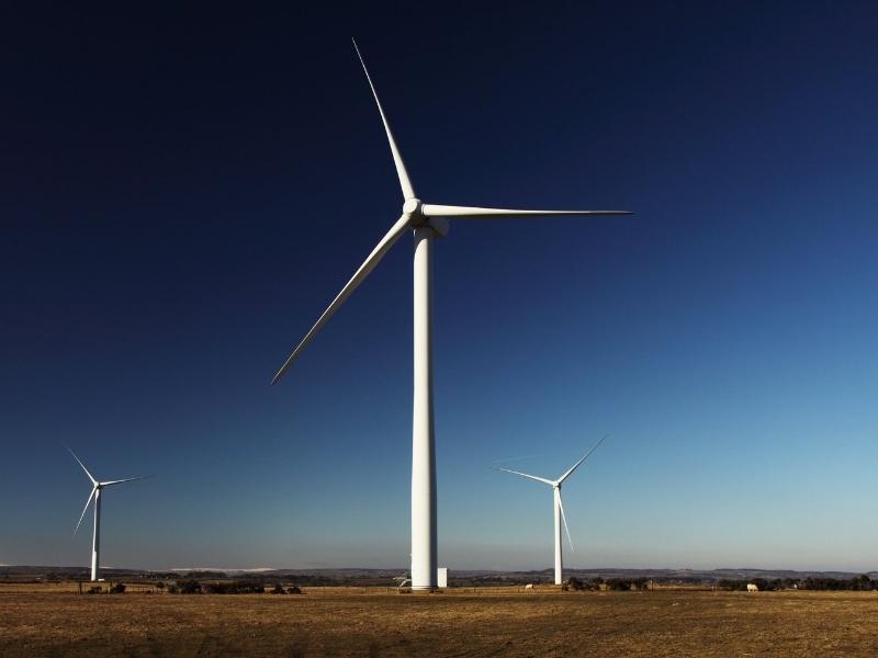 Large commercial wind turbines on grass with a blue sky