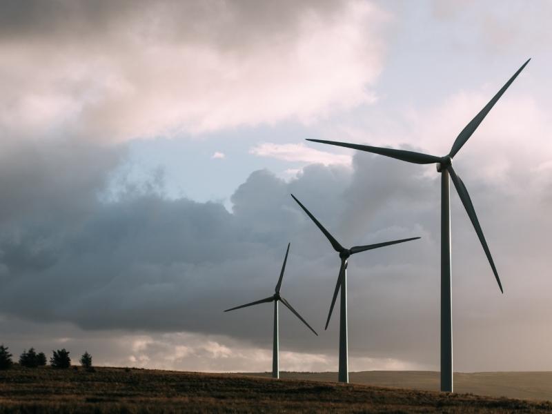 Three wind turbines in the country with cloudy skies