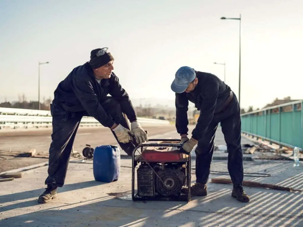 Two men starting a generator on a roof