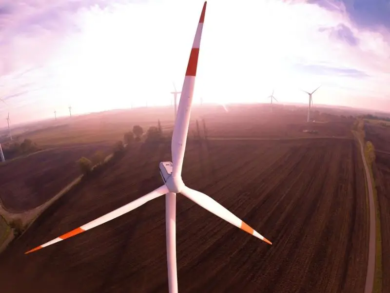 Wind turbine blades aerial shot overlooking fields