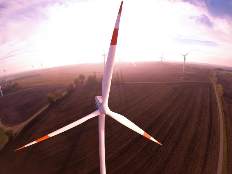 Wind turbine blades aerial shot overlooking fields