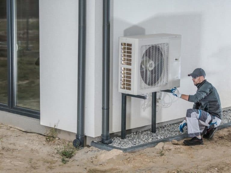 Engineer working on a heat pump outside of a house