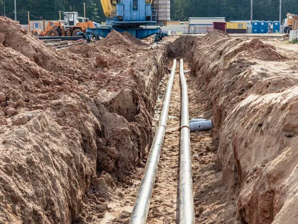 Laying heating pipes trench construction site. Energy efficient insulated pipes. Cold and hot water heating heating system for apartments and houses.