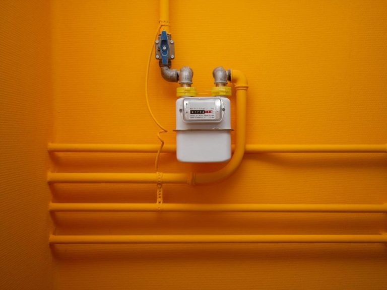 Pipes and gas meter on orange wall