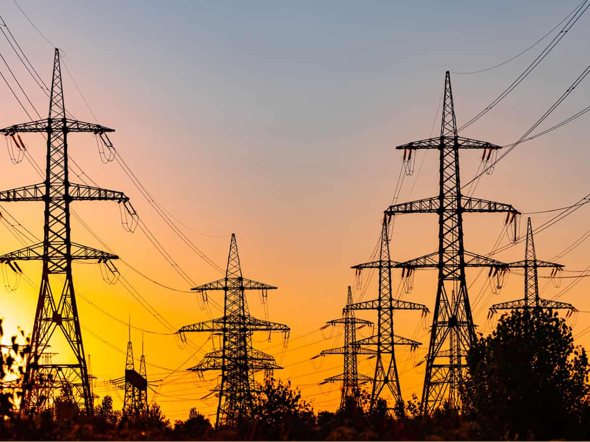 High voltage electric towers at golden sunset. Silhouettes of a number of electricity pylons and trees.