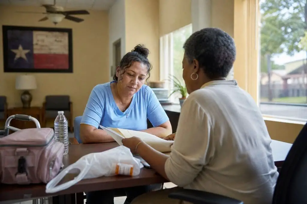 A Texas resident discusses utility assistance with a counselor at a community office while medical supplies rest nearby.