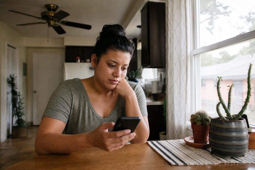 A Dallas resident uses a smartphone at a kitchen table while seeking same-day electricity service.